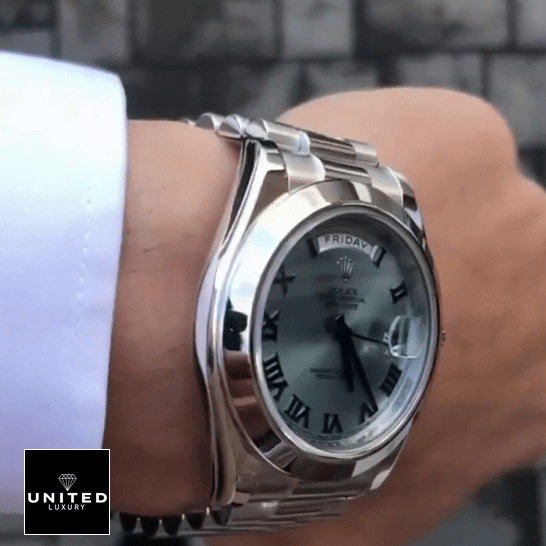 the man has a Rolex Day-Date II Stainless Steel Ice Blue Roman Dial 218206 Replica